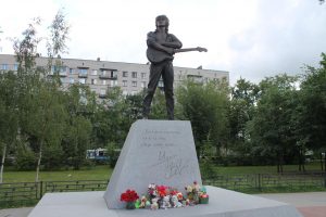 Tsoi monument in Saint Petersburg, August 2021: statue of a guitarist on pedastal, flowers paying hommage to the musician